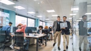 Business partners discussing new software on laptop while walking through office