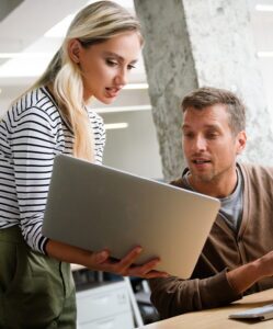 Man and woman coworkers using new software on laptop
