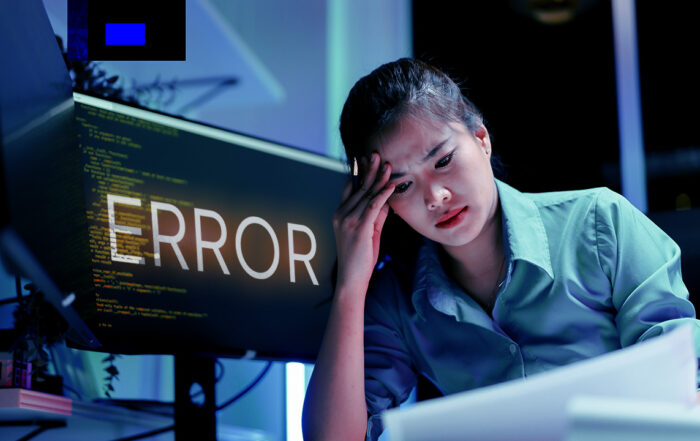 Frustrated and stressed business woman sifts through code with error sign on her computer