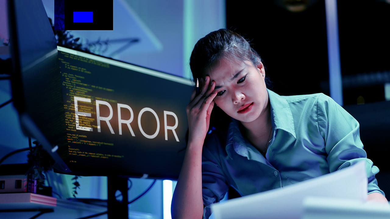 Frustrated and stressed business woman sifts through code with error sign on her computer